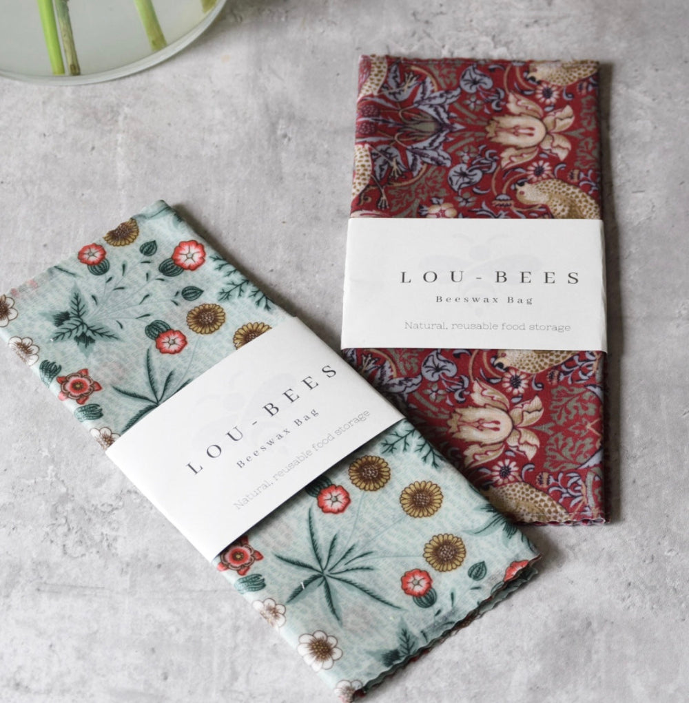 Two floral-patterned beeswax wraps with 'Lou-Bees' branding on a grey surface.