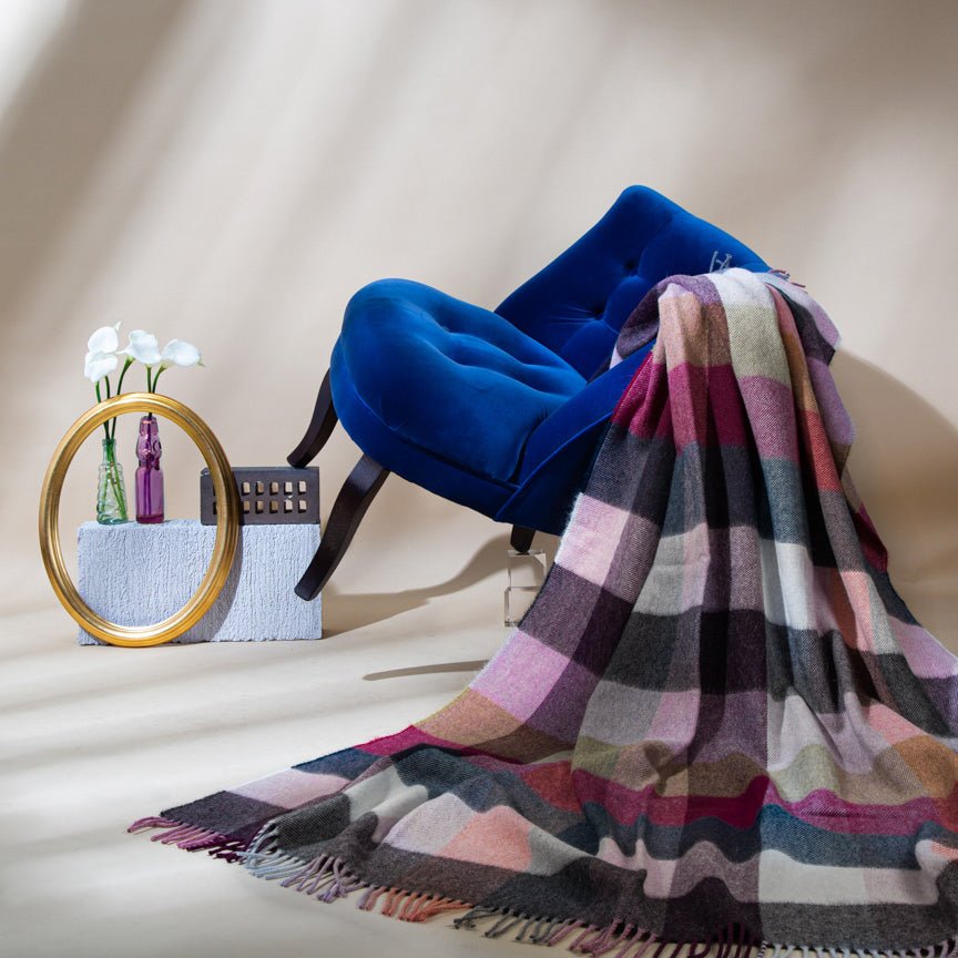 Multicolored checkered throw blanket draped over a chair with a neutral background