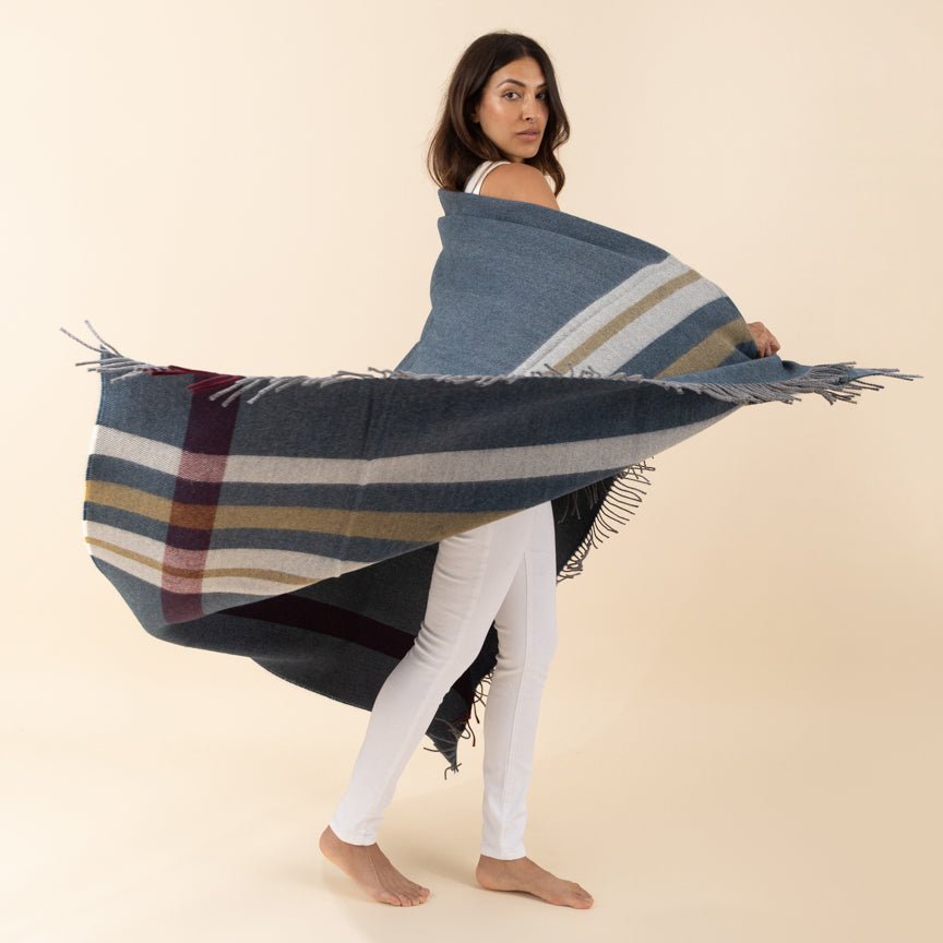 Woman holding a large plaid blanket against a beige background