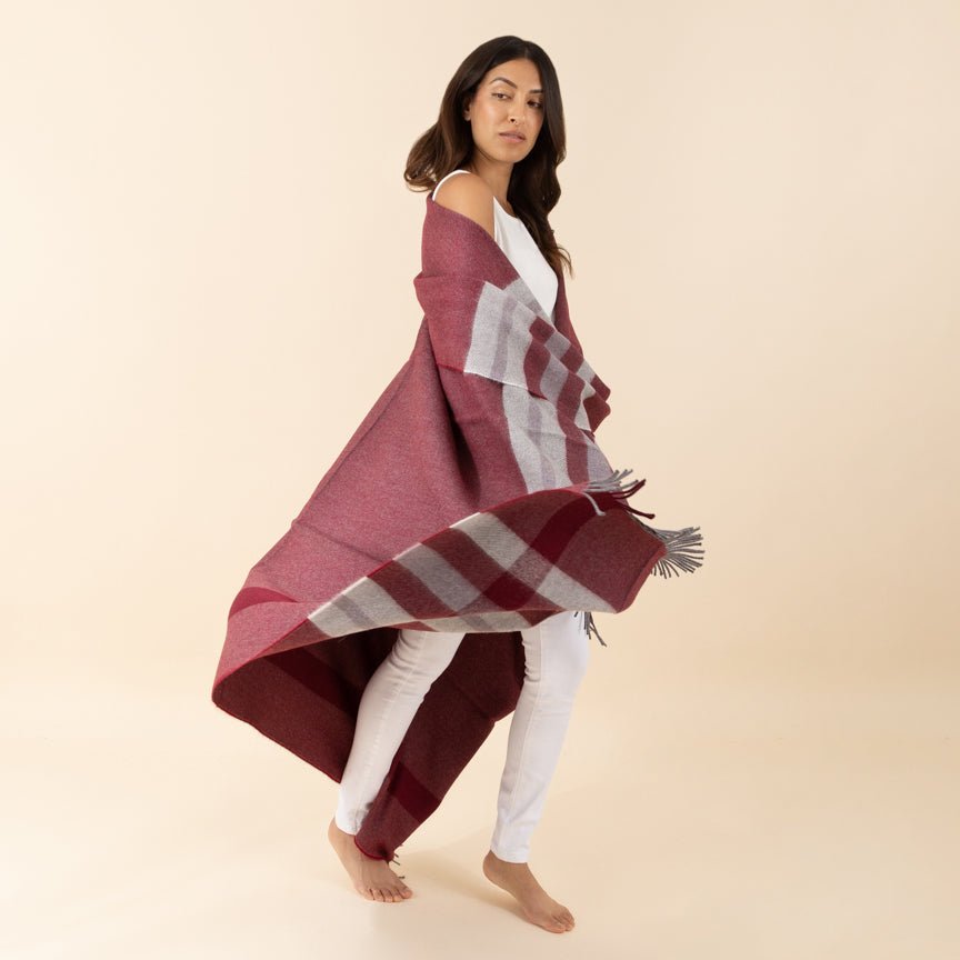 Woman wearing a red and white checkered alpaca blanket on a beige background