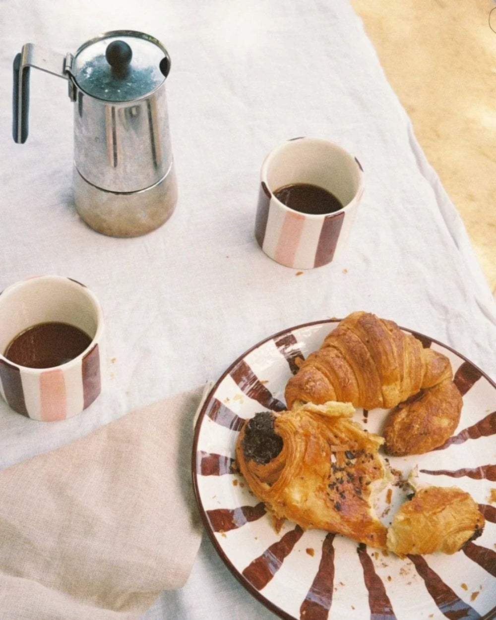 Woven Rosa Espresso dinner plate with pastries, coffee cups and a coffee pot