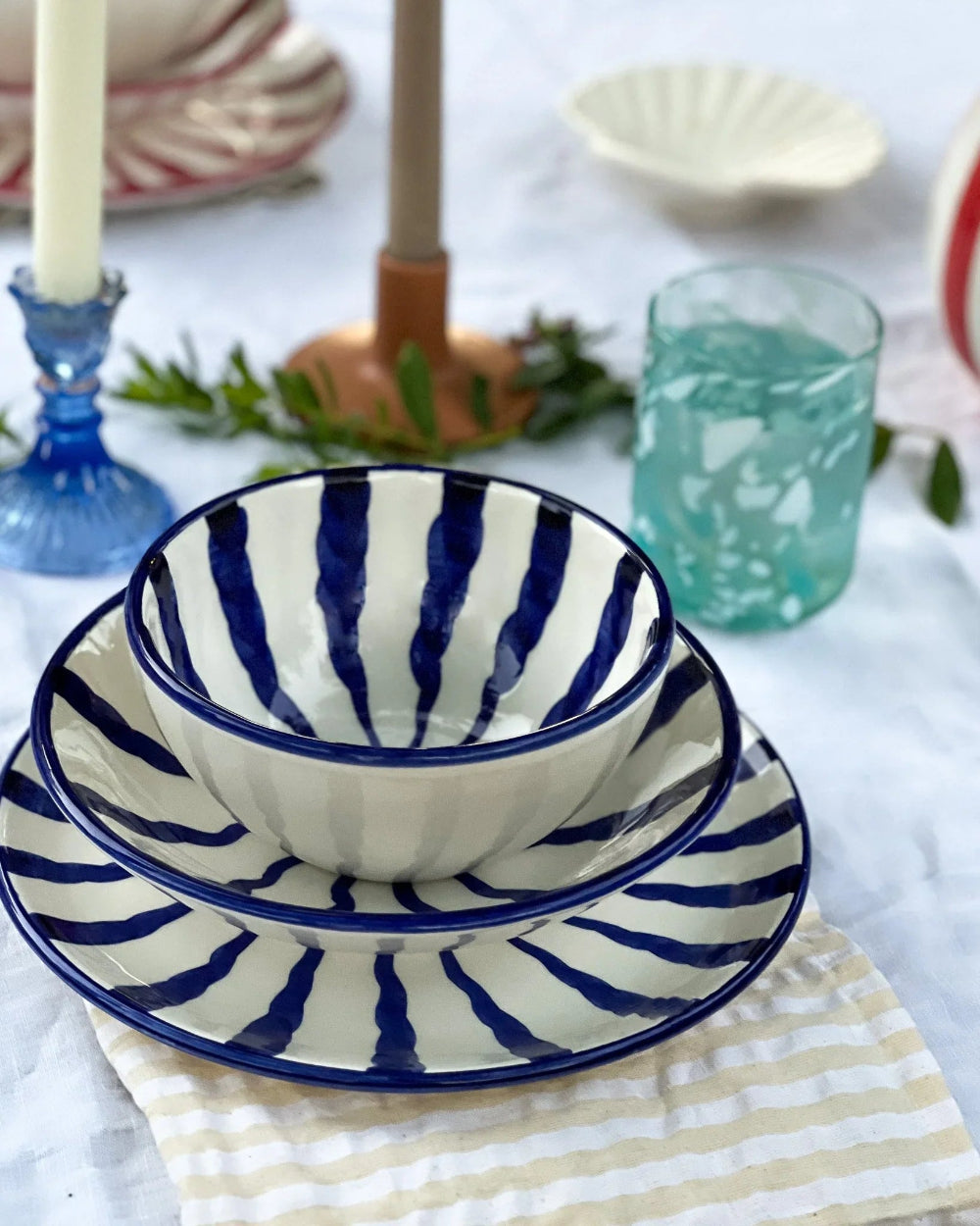 Set of blue and white striped ceramic bowls on a table with other decorative items.